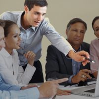 Business team discussing project with man pointing at the laptop